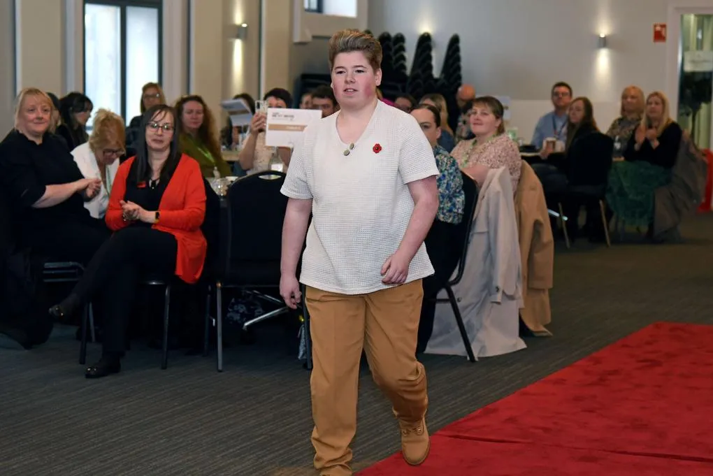 A girl walking past a crowd to accept an award at an awards ceremony