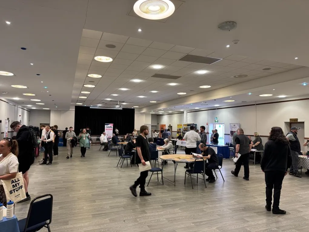Large room filled with employers stalls and people.