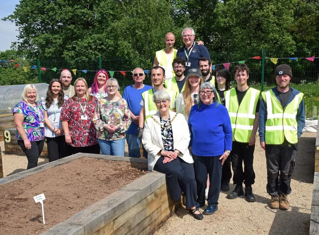 Group of participants and staff standing together in an outdoor community garden.