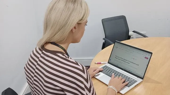 Person using laptop sitting at desk. 