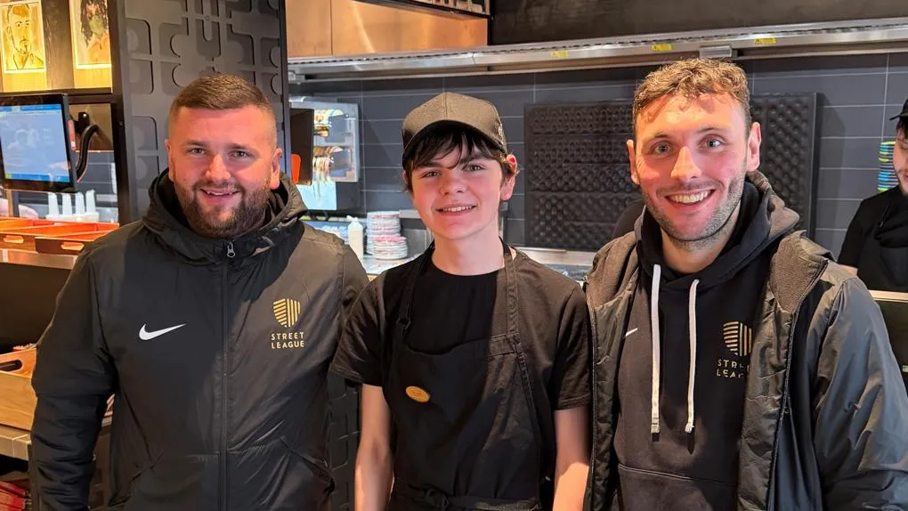 Participant standing with 2 key workers in restaurant