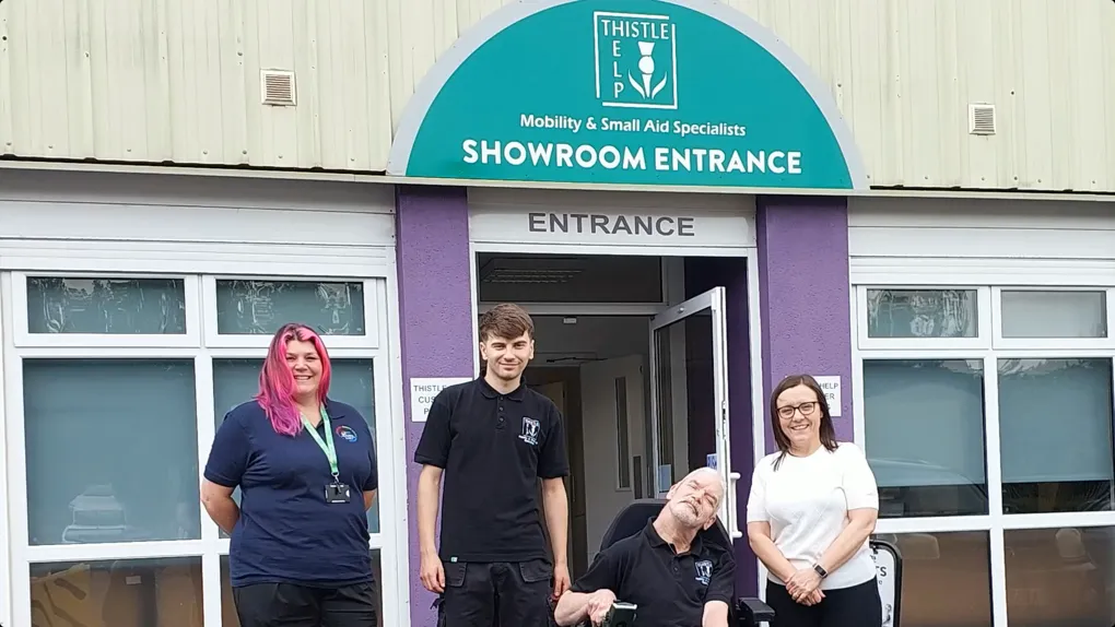 four people standing in front of business building entrance.