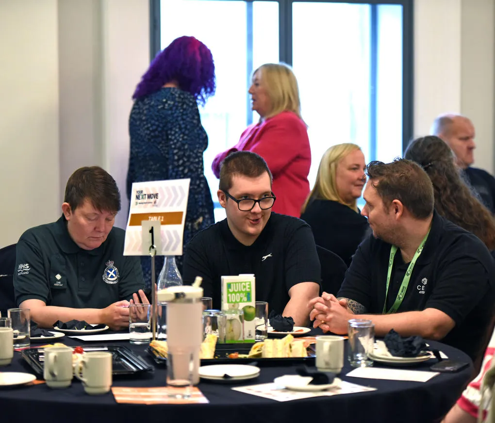 Ben sitting at a table with two others at an employability event